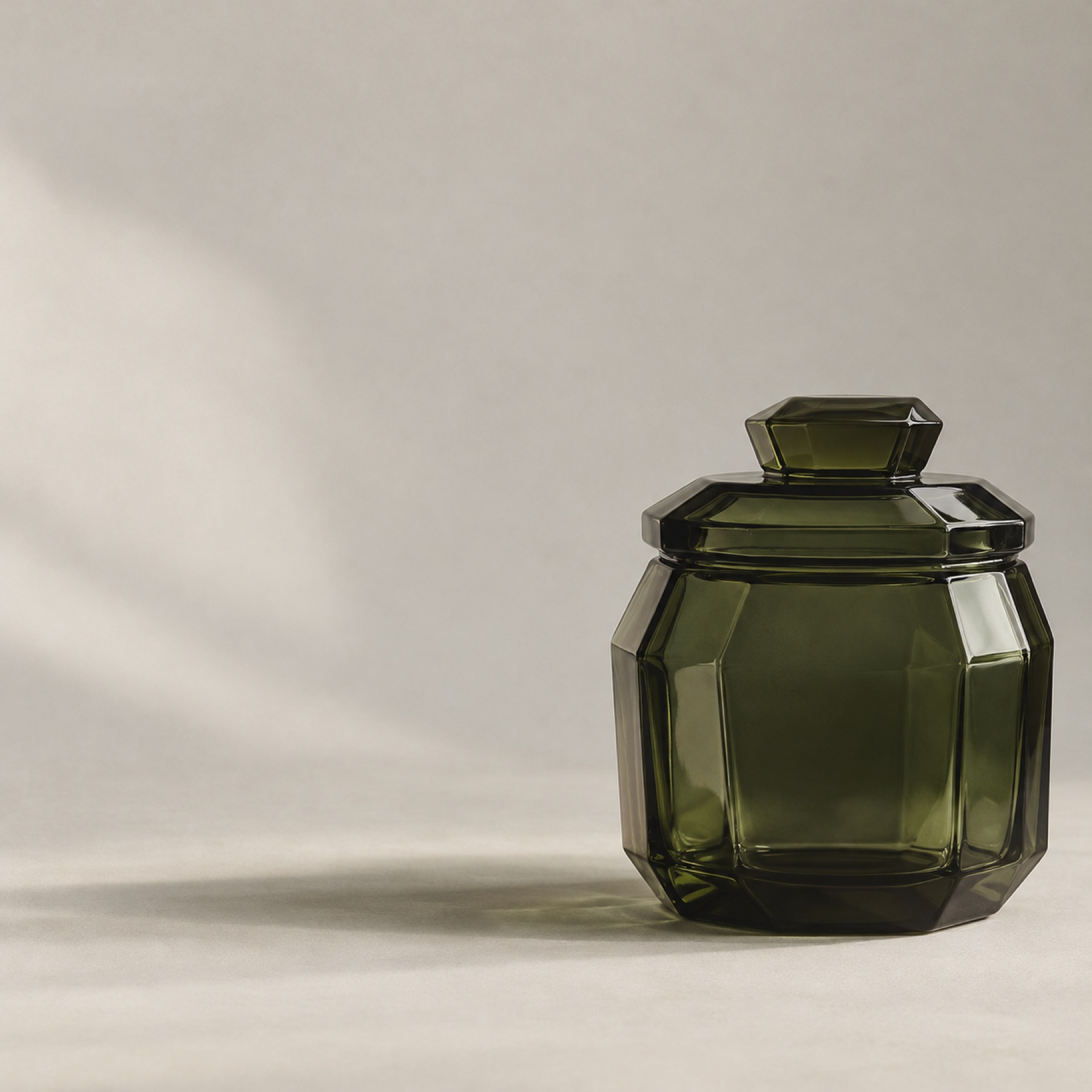 A faceted green glass coffee canister