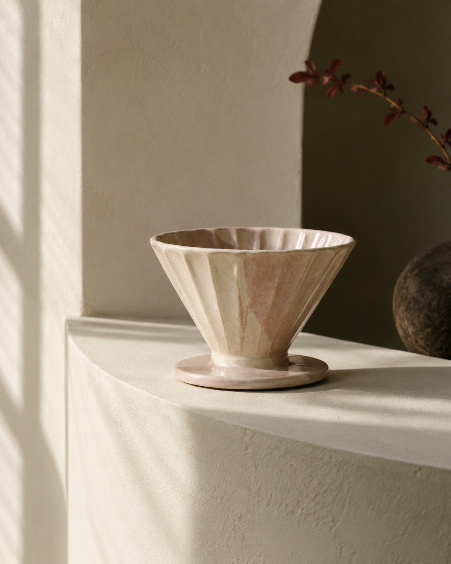 A pale ceramic pour-over dripper on a curved shelf
