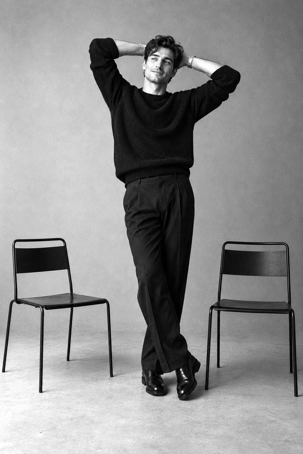 Man in a dark sweater standing between two black chairs
